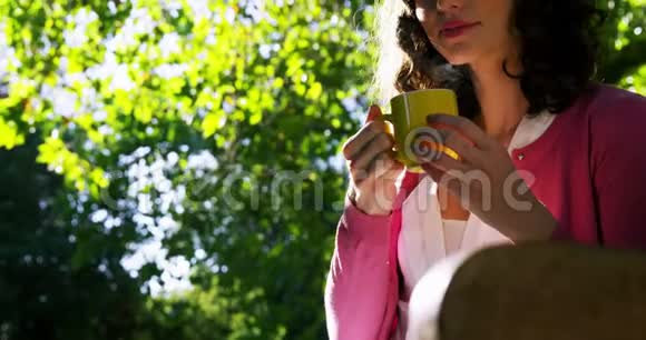 美丽的女人在花园里喝咖啡视频的预览图