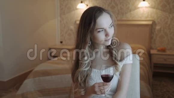 年轻的商务女性在她的酒店卧室放松从窗口的一杯红酒喝豪华客房视频的预览图