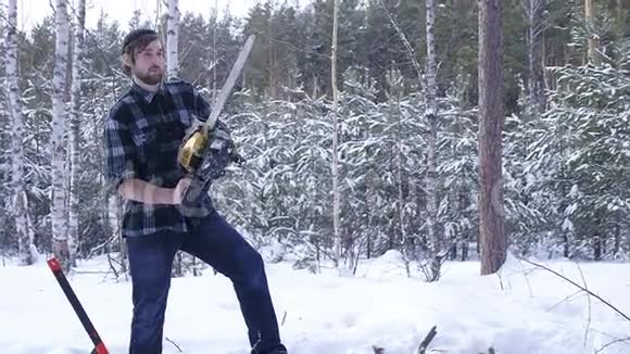 冬季白雪皑皑的森林里伐木工人用电锯手工锯木头视频的预览图