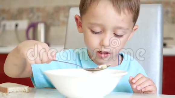 孩子正坐在厨房的桌子旁用勺子吃汤视频的预览图