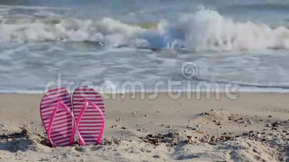 海边黄色沙滩上的粉色拖鞋视频的预览图