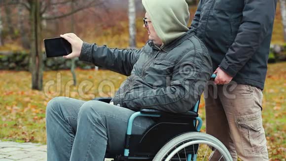 残疾人在轮椅上用智能手机拍摄助手在后面视频的预览图