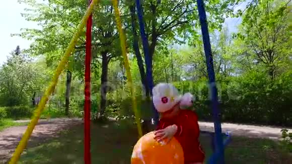 女孩在秋千上摇摆女孩拿着一个大橙色气球视频的预览图