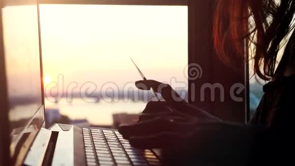 在美丽的日落时分一位女士在城市背景模糊的背景下使用信用卡上网并使用笔记本电脑视频的预览图