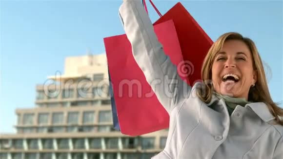 快乐的女人展示她的购物袋视频的预览图