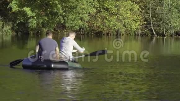 两个穿着橡皮船的渔夫在河上划桨人在阳光明媚的森林里湖上钓鱼斯特拉克河视频的预览图