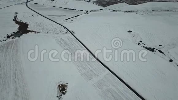 在积雪覆盖的田野背景下鸟瞰冬季道路顶部视图视频的预览图