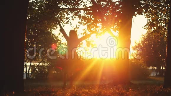 快乐的女孩在秋天的公园里在日落的时候在阳光的背景下缓慢地旋转着1920x1080视频的预览图