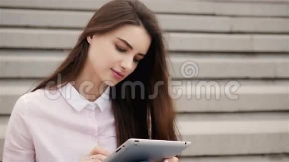年轻漂亮的学生女孩在外面用平板电脑很漂亮的少女在空中看书视频的预览图
