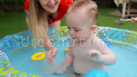 可爱的微笑宝宝在后院的充气游泳池玩耍视频的预览图