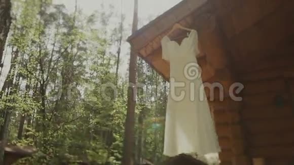 白色婚纱挂在木屋上太阳在树上刹车视频的预览图