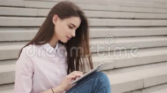 年轻漂亮的学生女孩在外面用平板电脑很漂亮的少女在空中看书视频的预览图