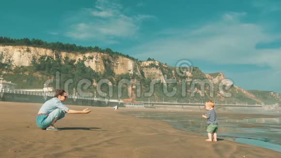 年轻漂亮的母亲和她美丽的小儿子在大西洋的早晨海滩上度过时光视频的预览图