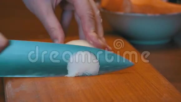 女厨师在家庭厨房的木制剪板上剪洋葱视频的预览图