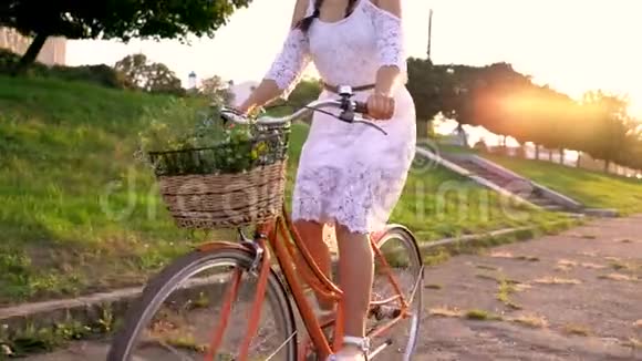 日落时骑自行车的年轻美女慢动作视频的预览图