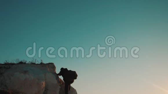一位游客在日落探险时爬上山顶的剪影男人的轮廓视频的预览图