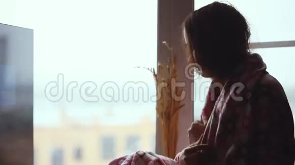 坐在窗台上坐在格子里的沮丧悲伤的女人1920x1080视频的预览图