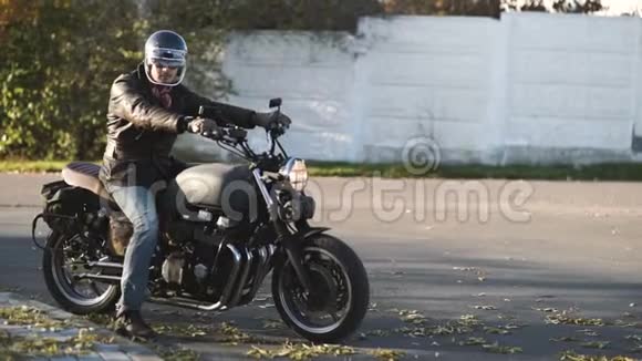 在秋日阳光明媚的日子骑着古老的定制咖啡馆骑着摩托车在乡间小路上视频的预览图