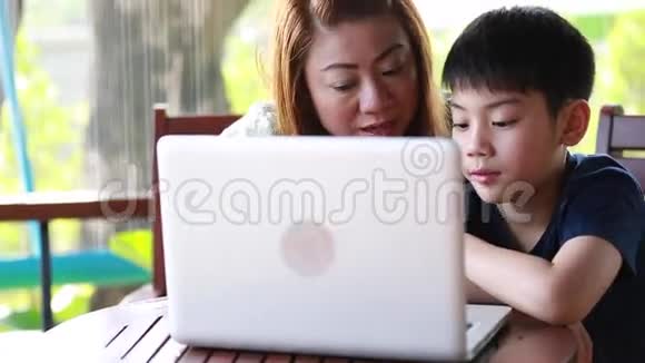 年轻快乐的母亲带着孩子在露台上使用笔记本电脑视频的预览图