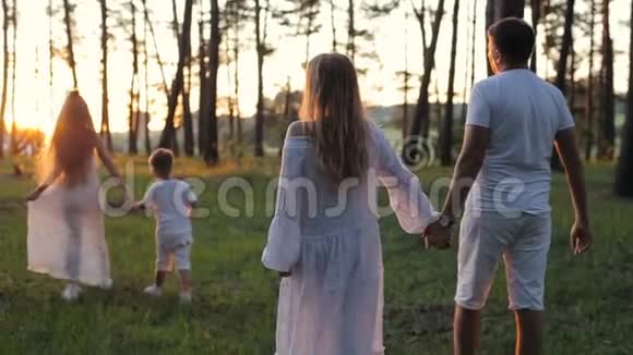 四口之家在森林里散步穿着白色衣服和草帽的父母和孩子都很高兴视频的预览图