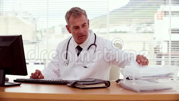 医生在搜索文件和使用他的电脑视频的预览图