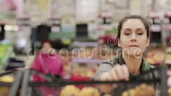 年轻的女人在商店的货架上选择成熟的橘子视频的预览图