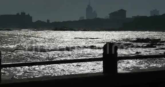 黄昏时分人们沿着海岸漫步海滨城市建筑和海洋波浪视频的预览图