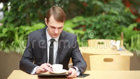 商人坐在咖啡馆的桌子上工作平板电脑视频的预览图