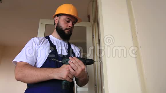 建筑工人和杂工从事公寓改造工作筑工用电钻钻钉孔入墙门视频的预览图