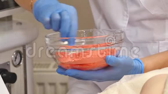 美容师用玻璃碟子从管子里挤出奶油双手戴医用手套视频的预览图
