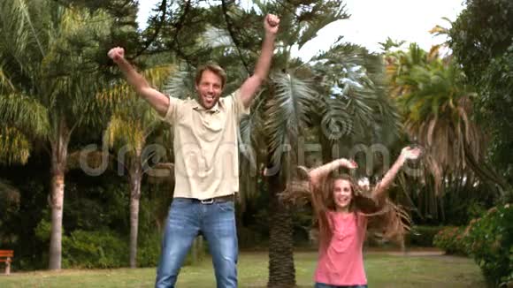 快乐的父亲和女儿跳在蹦床上视频的预览图