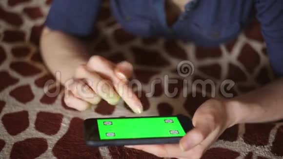年轻女子在家玩智能手机长颈鹿床罩绿色屏幕只准备手视频的预览图