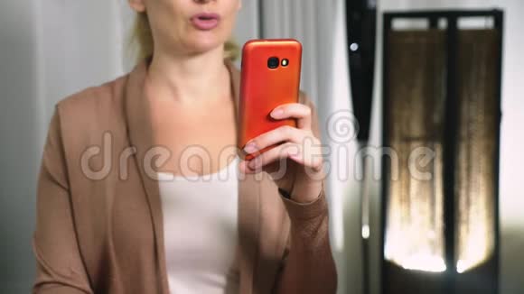 女人用智能手机上的视频交流调情一个女人在视频通话中通过网络发送一个吻视频的预览图
