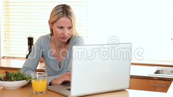 有笔记本电脑的女人喝橙汁视频的预览图