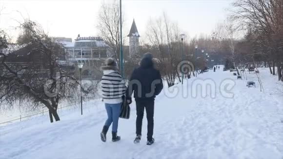 年轻夫妇在公园里散步冬季可爱的情侣在冬季公园散步微笑视频的预览图