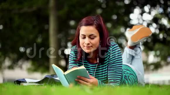 躺在草地上看书听音乐的漂亮学生视频的预览图