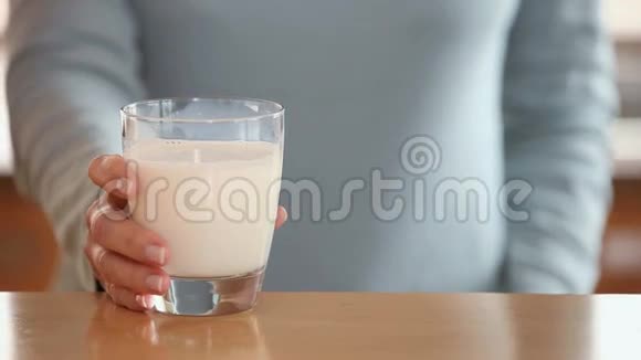 女人从桌子上举起一杯牛奶视频的预览图