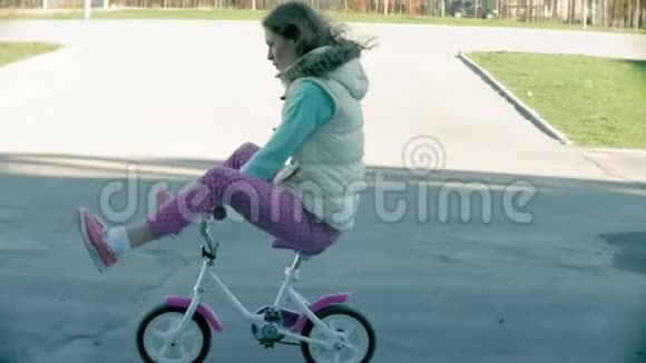 在温暖的春天里一位笑着的母亲把她的女儿推到前面她教她骑自行车视频的预览图