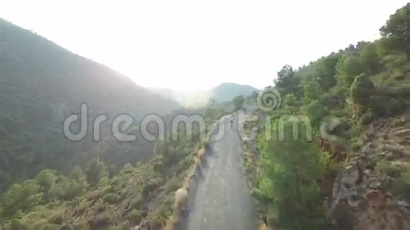 骑自行车者在高坡山地公路上靠阳光的鸟瞰图视频的预览图
