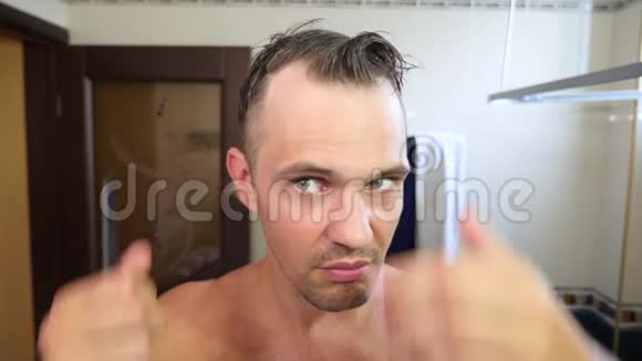 年轻有魅力的男人在浴室里检查一条后退的发际线秃头4k慢动作视频的预览图
