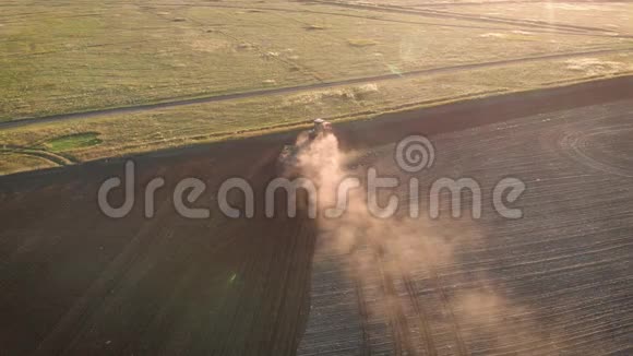 日落时分在农田上鸟瞰现代红色拖拉机拖拉机耕地和耕地视频的预览图