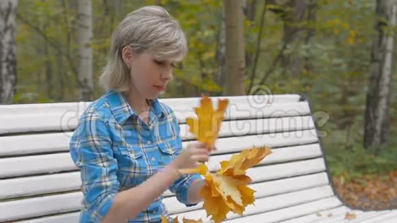 年轻女子在公园里织了一个枫叶花环视频的预览图