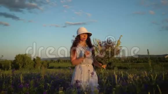 年轻的女人带着一束田野的花走着视频的预览图