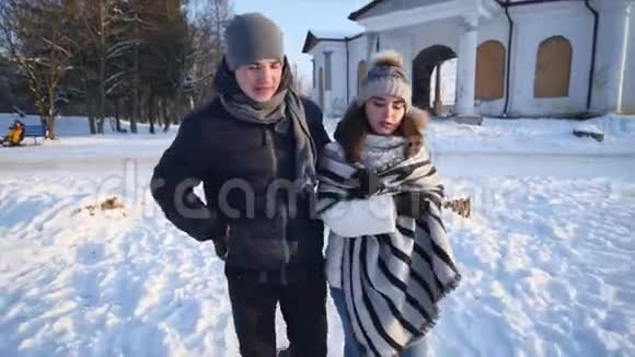 年轻夫妇在公园里散步冬季可爱的情侣在冬季公园散步微笑视频的预览图