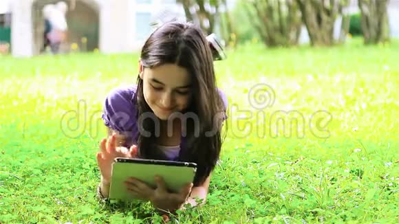 在草地上使用数字平板电脑的少女视频的预览图