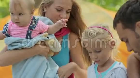 两个小女孩坐在野餐的父母视频的预览图