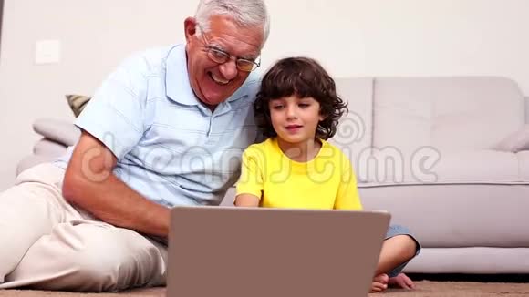 老人坐在地板上孙子用笔记本电脑视频的预览图