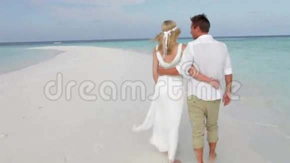 婚礼时夫妇沿着海滩散步的后景视频的预览图