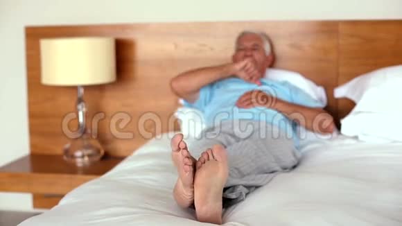 老人躺在床上打哈欠和伸展视频的预览图