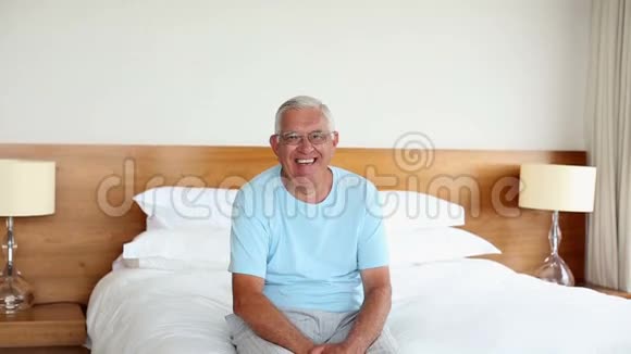 早上坐在床上对着镜头微笑的老人视频的预览图